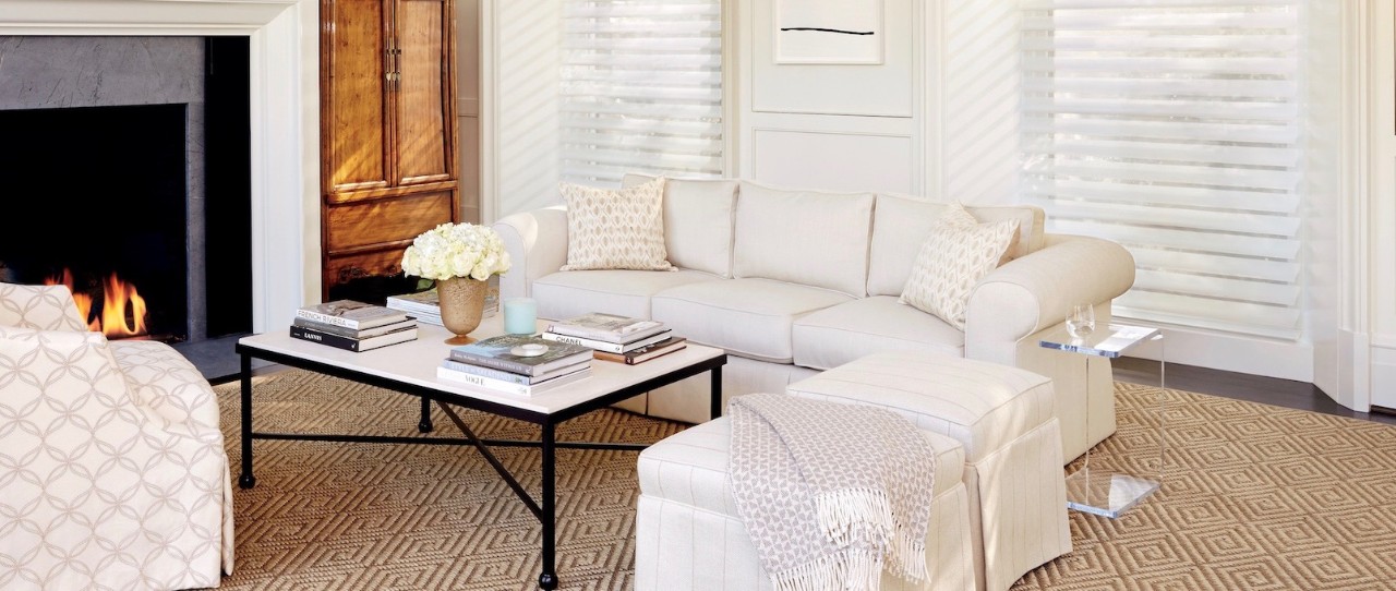 Living room with white sofa and fire place. Silhouette window treatments in the large windows